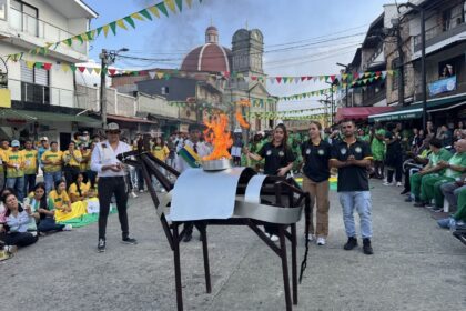 Figura 1. La mula de hierro y el pebetero encendido en el parque principal de Valdivia. Nota: los deportistas locales portan la antorcha, junto al artefacto simbólico central de los Juegos Campesinos. Al fondo, la iglesia del municipio. En términos de Bijker (1995), la mula de hierro funciona como un artefacto con flexibilidad interpretativa: homenaje a la vida campesina, espejo de identidad montañera e imagen condensadora de toda la narrativa mediática. Valdivia, Antioquia, 10 de septiembre de 2025. Fotografía del autor.
