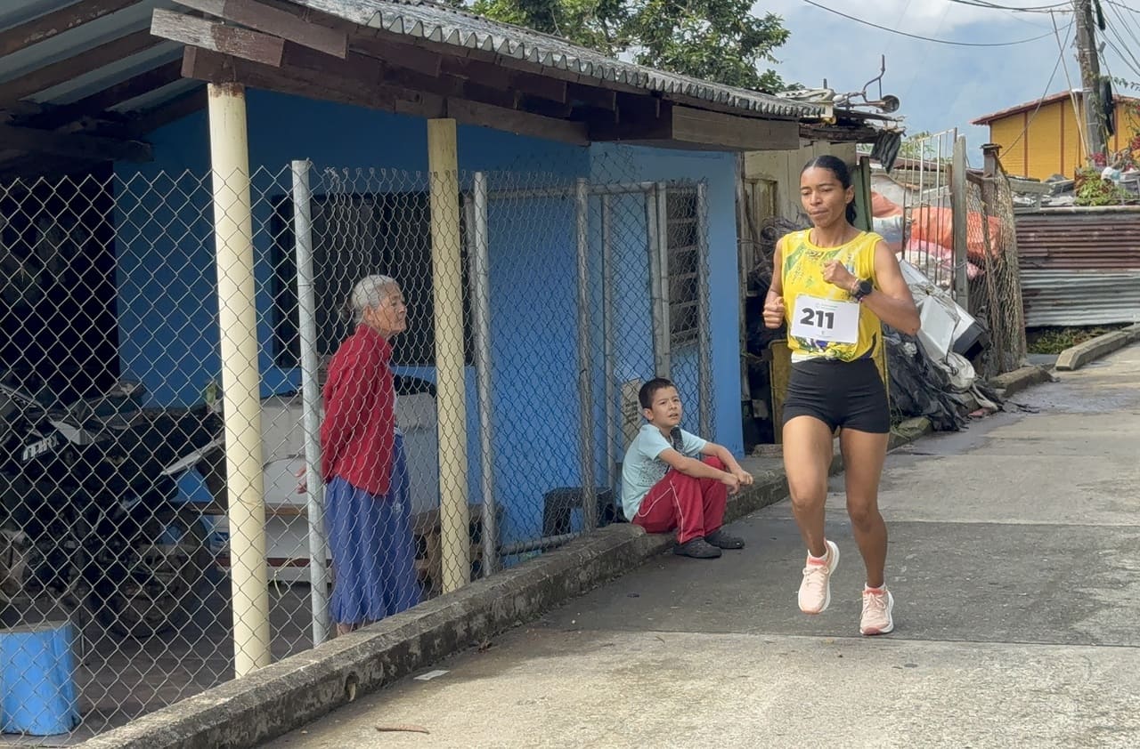 Figura 4. Elizabeth Espinosa Patiño compite en las calles de Valdivia. Nota: la atleta de Santa Rosa de Osos, vendedora y madre, corre por las calles del municipio bajo la mirada de sus habitantes. Un niño y su abuela la observan desde el andén. La imagen sintetiza la intersección mujer-madre-trabajadora-campesina-deportista y el ejercicio de agencia pública en un territorio asediado. Valdivia, Antioquia, 12 de septiembre de 2025. Fotografía del autor.